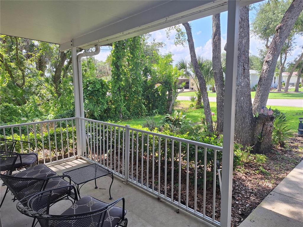 A covered porch with metal railings overlooks a yard with trees and a street — 301 WATERLANDING DRIVE, OAK HILL, FL