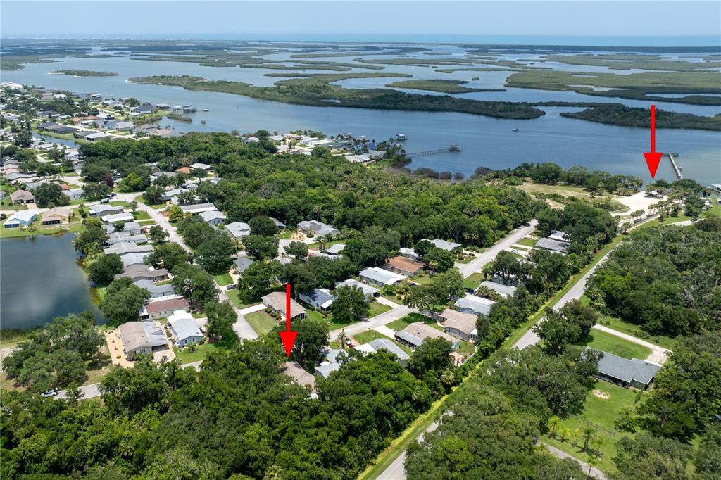 An aerial view shows a residential neighborhood near a body of water with two red arrows — 301 WATERLANDING DRIVE, OAK HILL, FL