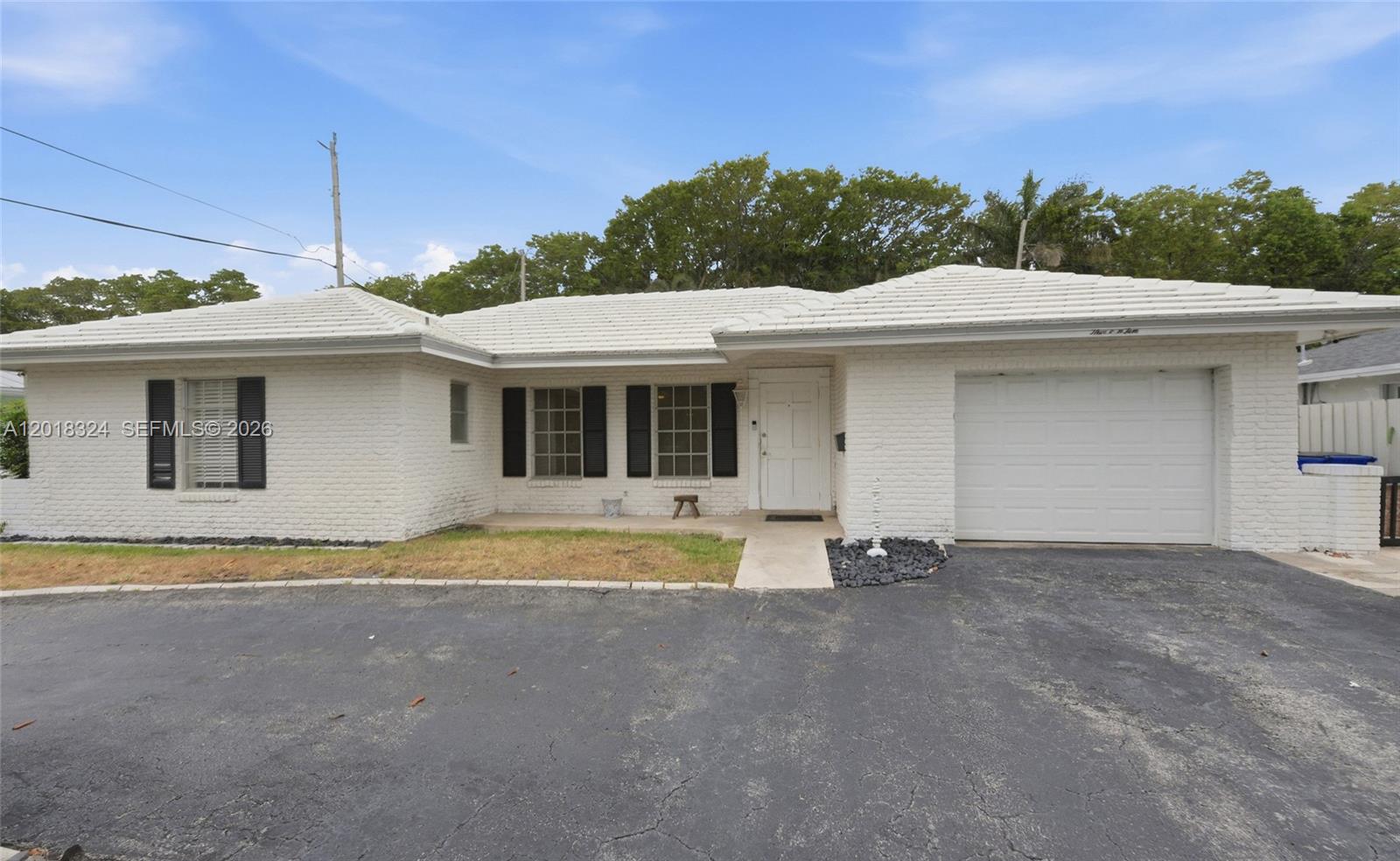 A single-story white brick house features a tiled roof, black shutters, and an attached garage — 1310 SE 14th Ct, Deerfield Beach FL 33441, DEERFIELD BEACH, FL