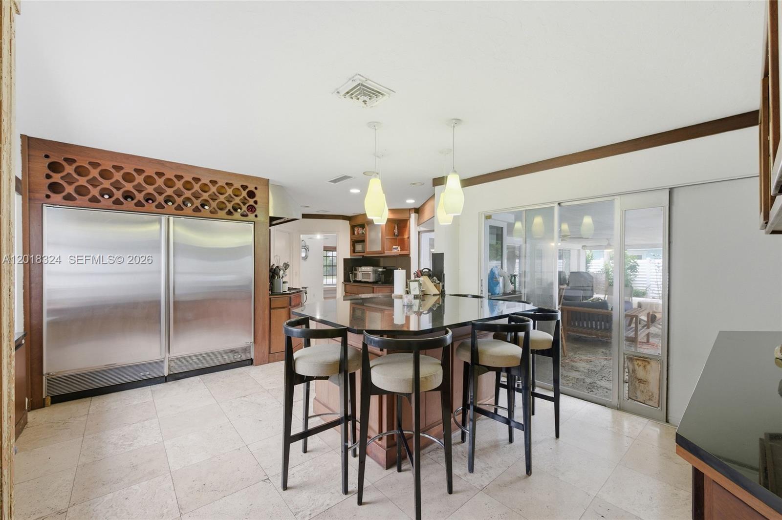 A kitchen features a large island with bar stools, stainless steel appliances, and tile flooring — 1310 SE 14th Ct, Deerfield Beach FL 33441, DEERFIELD BEACH, FL