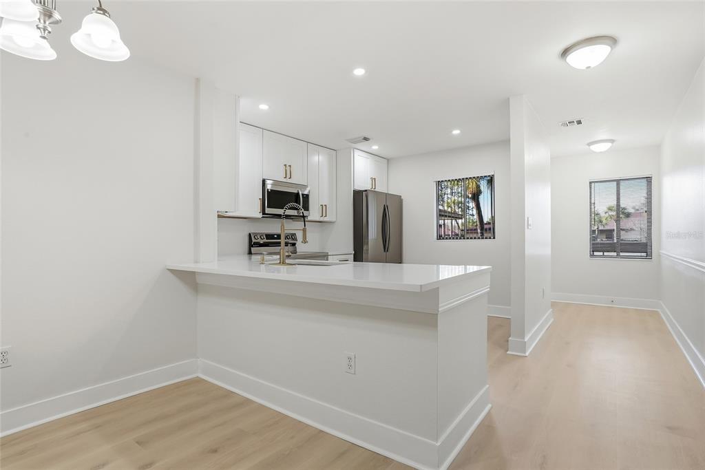 A modern kitchen features white cabinets, stainless steel appliances, and a breakfast bar — 2682 SABAL SPRINGS CIRCLE UNIT 204, CLEARWATER, FL