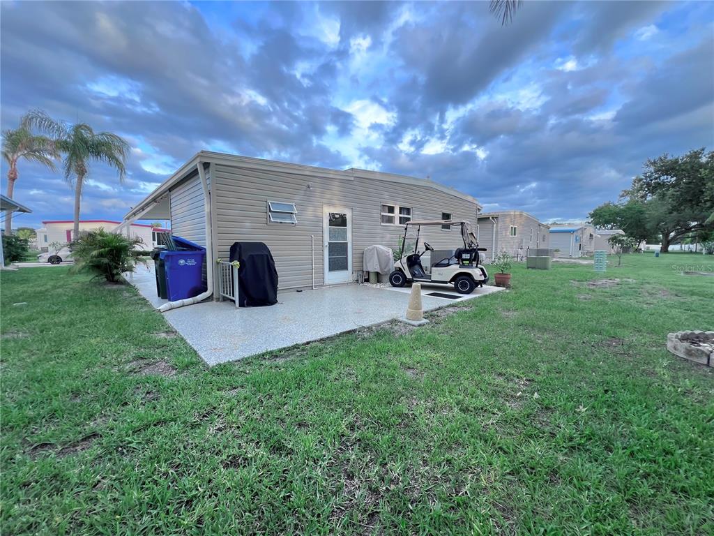 The exterior of a mobile home features a concrete patio, a golf cart, and siding — 1100 BELCHER ROAD S UNIT 633, LARGO, FL