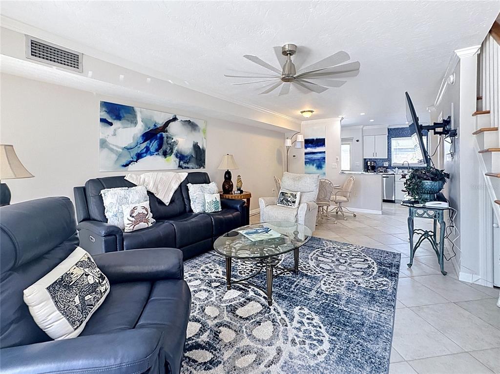 A living room features a dark leather sofa, a glass coffee table, and a patterned rug — 120 52ND STREET, HOLMES BEACH, FL