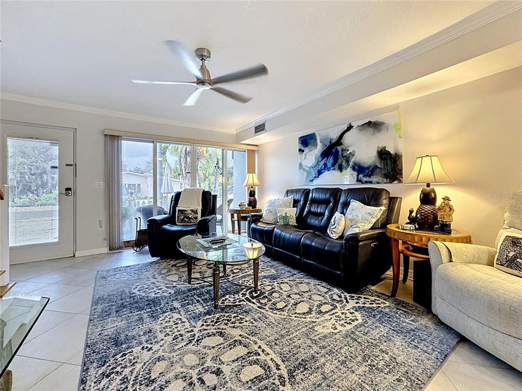 A living room features a black leather sofa, patterned area rug, and sliding glass doors — 120 52ND STREET, HOLMES BEACH, FL