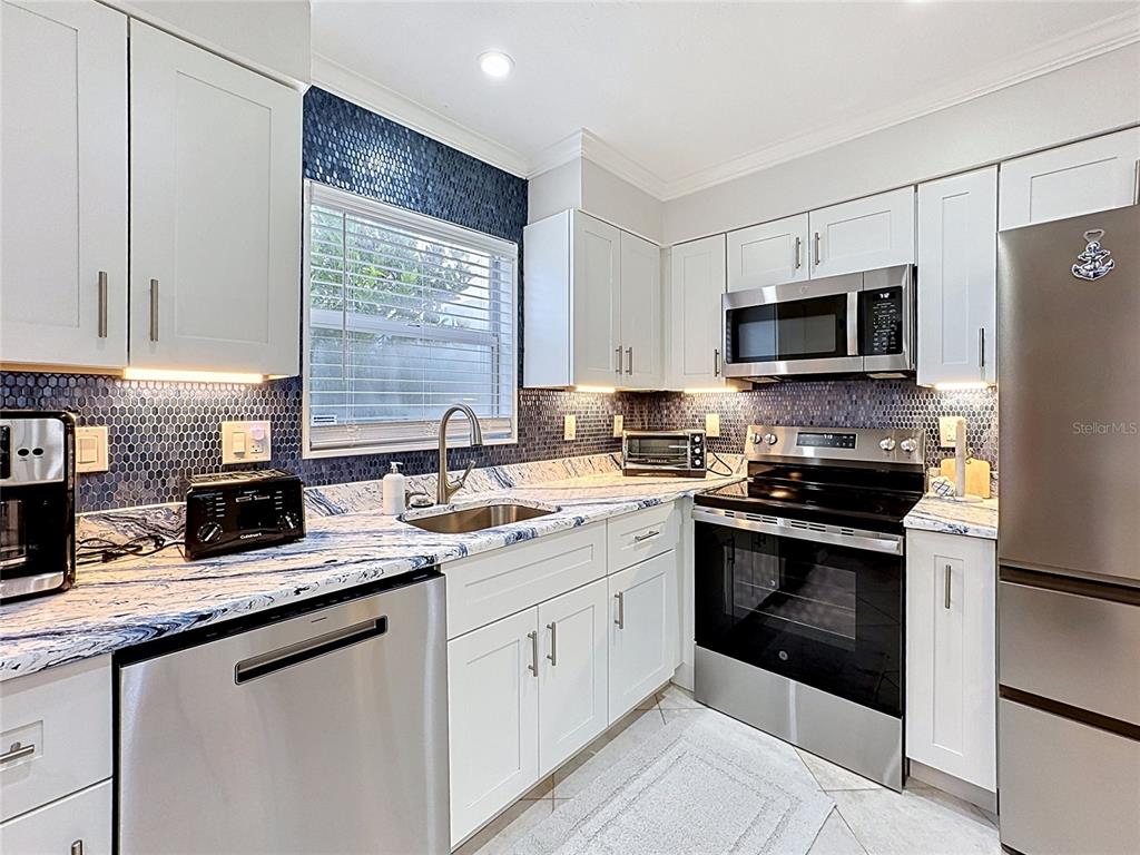 A kitchen features white cabinets, blue patterned countertops, and a dark blue honeycomb tile backsplash — 120 52ND STREET, HOLMES BEACH, FL
