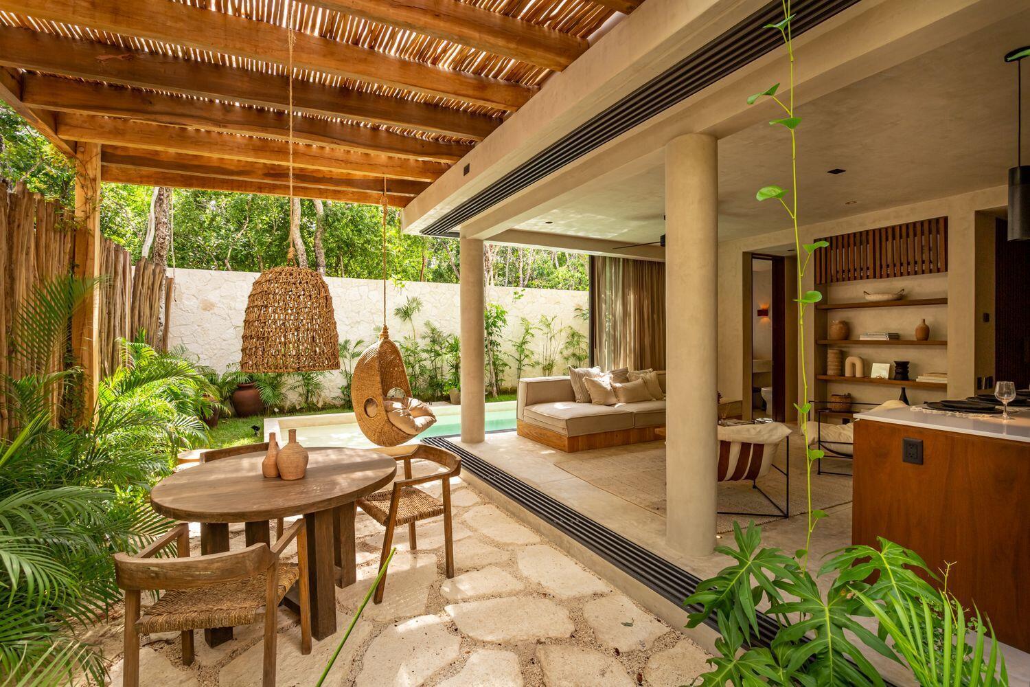 A patio with a wooden dining set, hanging chair, and pool overlooking an indoor living area — Amari Tulum 10 Avenida Norte & Calle Palma, FL