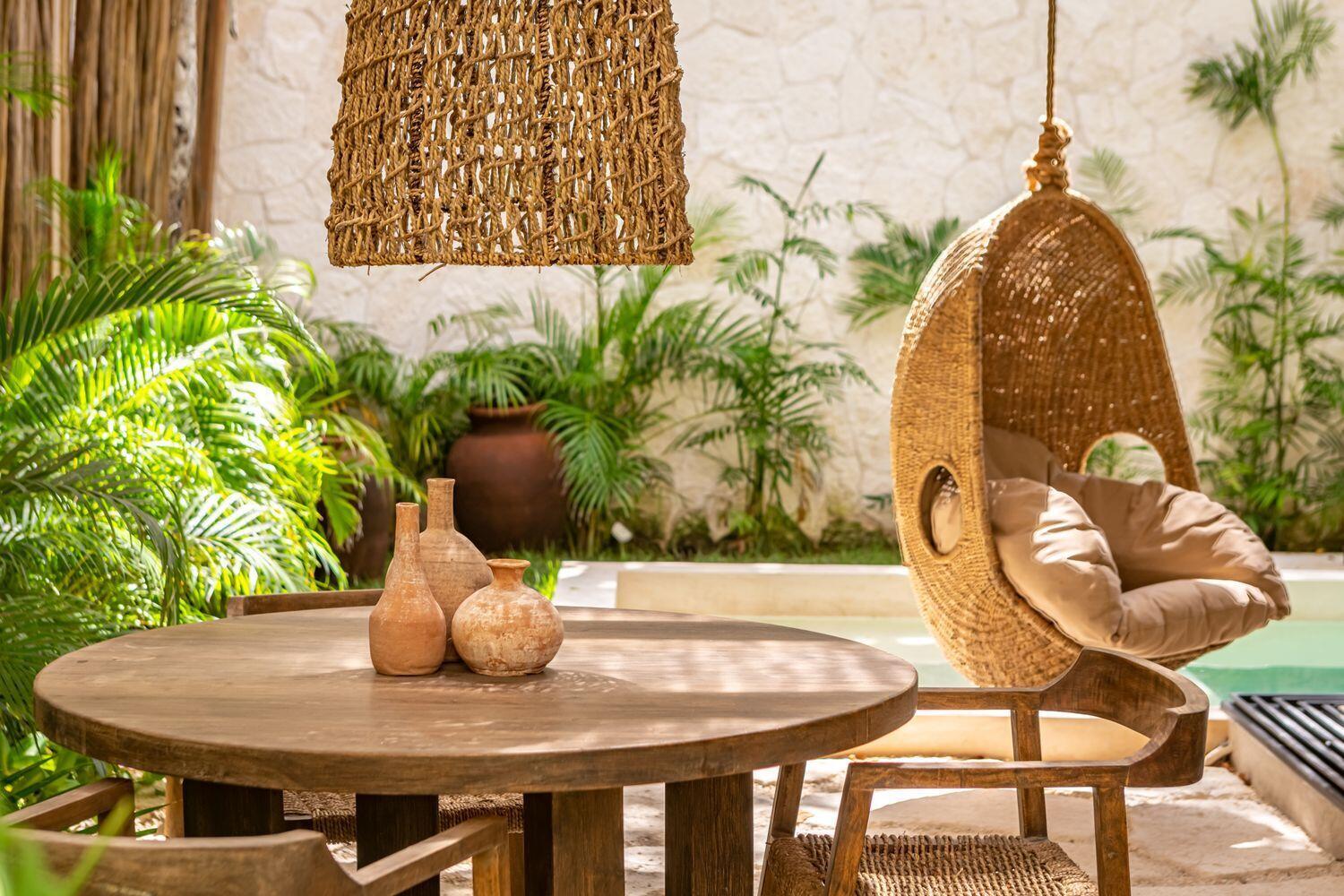 A round wooden table with clay vases sits on a patio near a hanging chair — Amari Tulum 10 Avenida Norte & Calle Palma, FL
