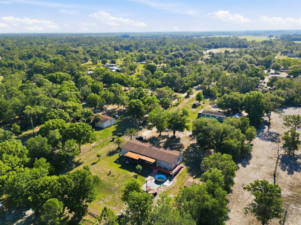 An aerial view shows a single-story house with a pool in a wooded rural area — 1560 MCCLELLAN ROAD, FROSTPROOF, FL