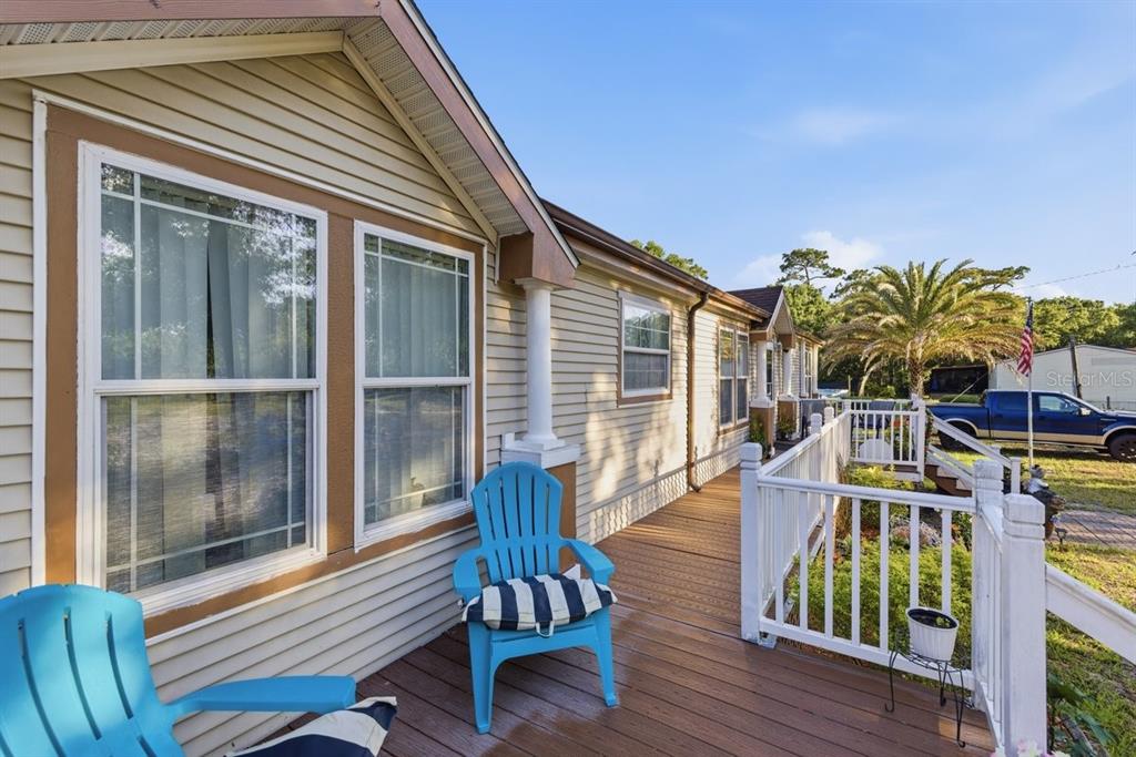 A wooden deck with blue chairs runs along the side of a tan vinyl-sided house — 1560 MCCLELLAN ROAD, FROSTPROOF, FL