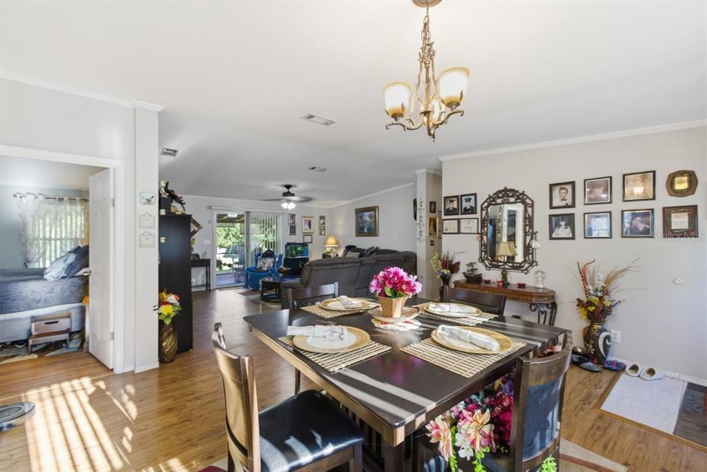 A dining area with a dark wood table and chairs opens into a living room — 1560 MCCLELLAN ROAD, FROSTPROOF, FL