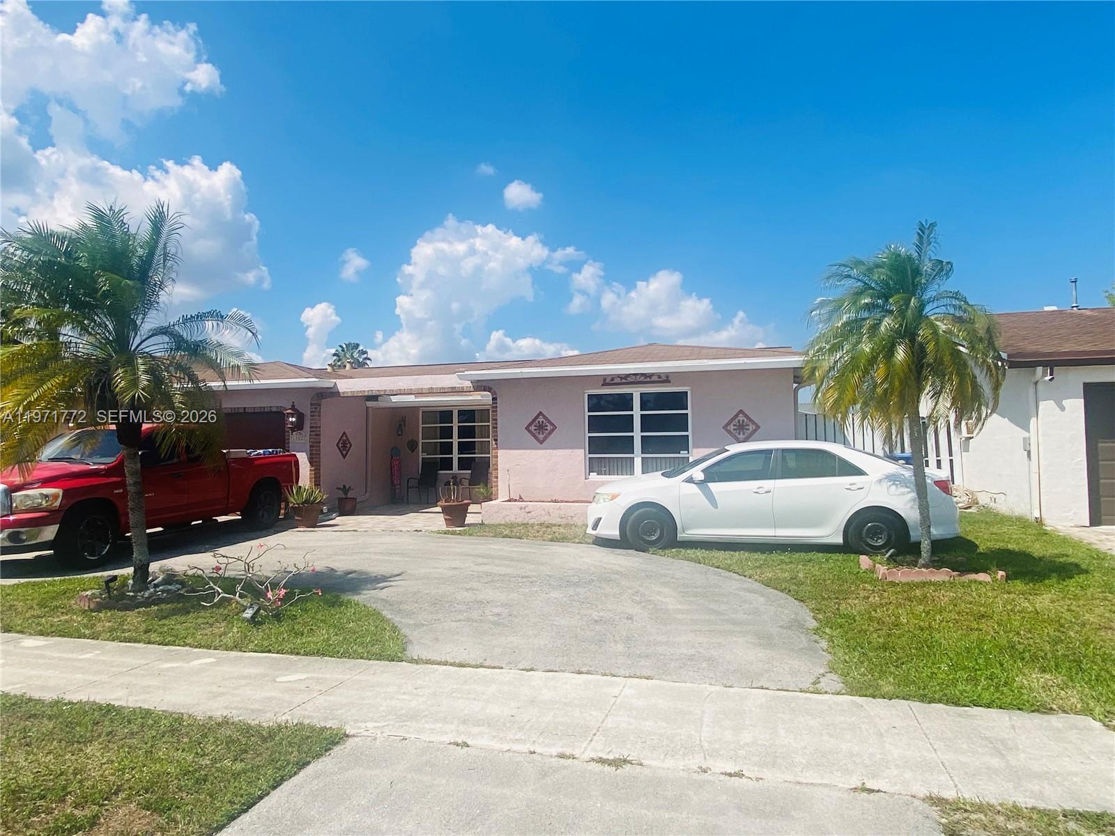 A single-story pink house features a concrete driveway, two palm trees, and two parked vehicles — 11827 NW 39th St, Sunrise FL 33323, SUNRISE, FL