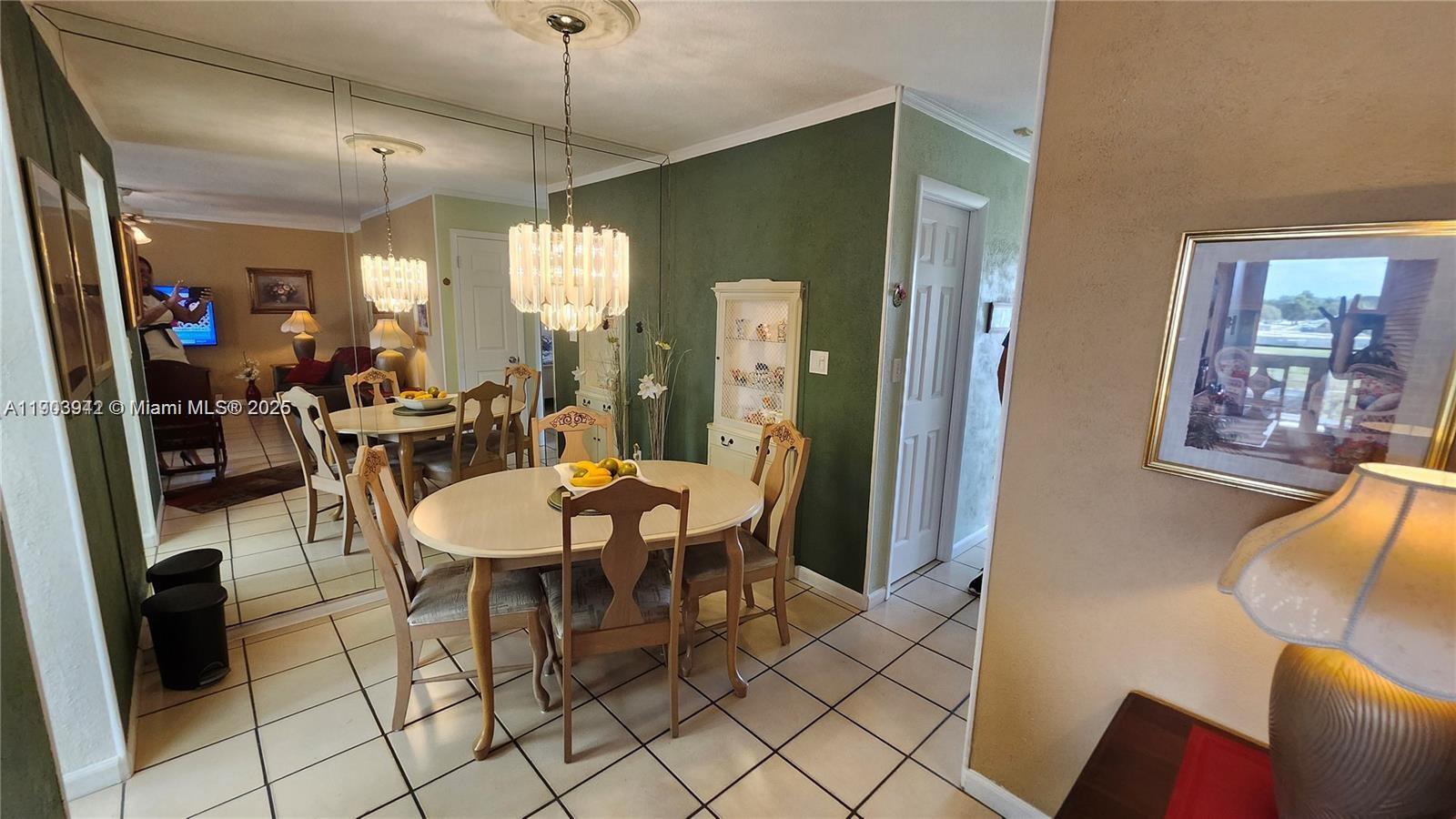 A dining room features a round table, a crystal chandelier, and a mirrored wall — 16901 NE 13th Ave # 306, Miami FL 33162, MIAMI, FL
