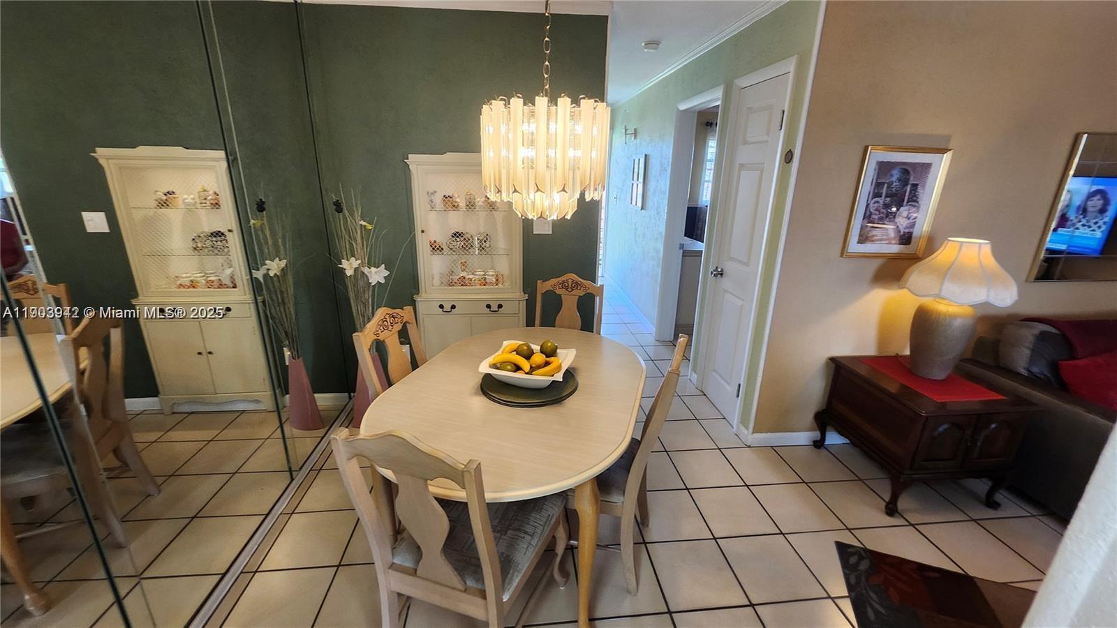 A dining area features a light-colored table, chairs, a chandelier, and a mirrored wall — 16901 NE 13th Ave # 306, Miami FL 33162, MIAMI, FL