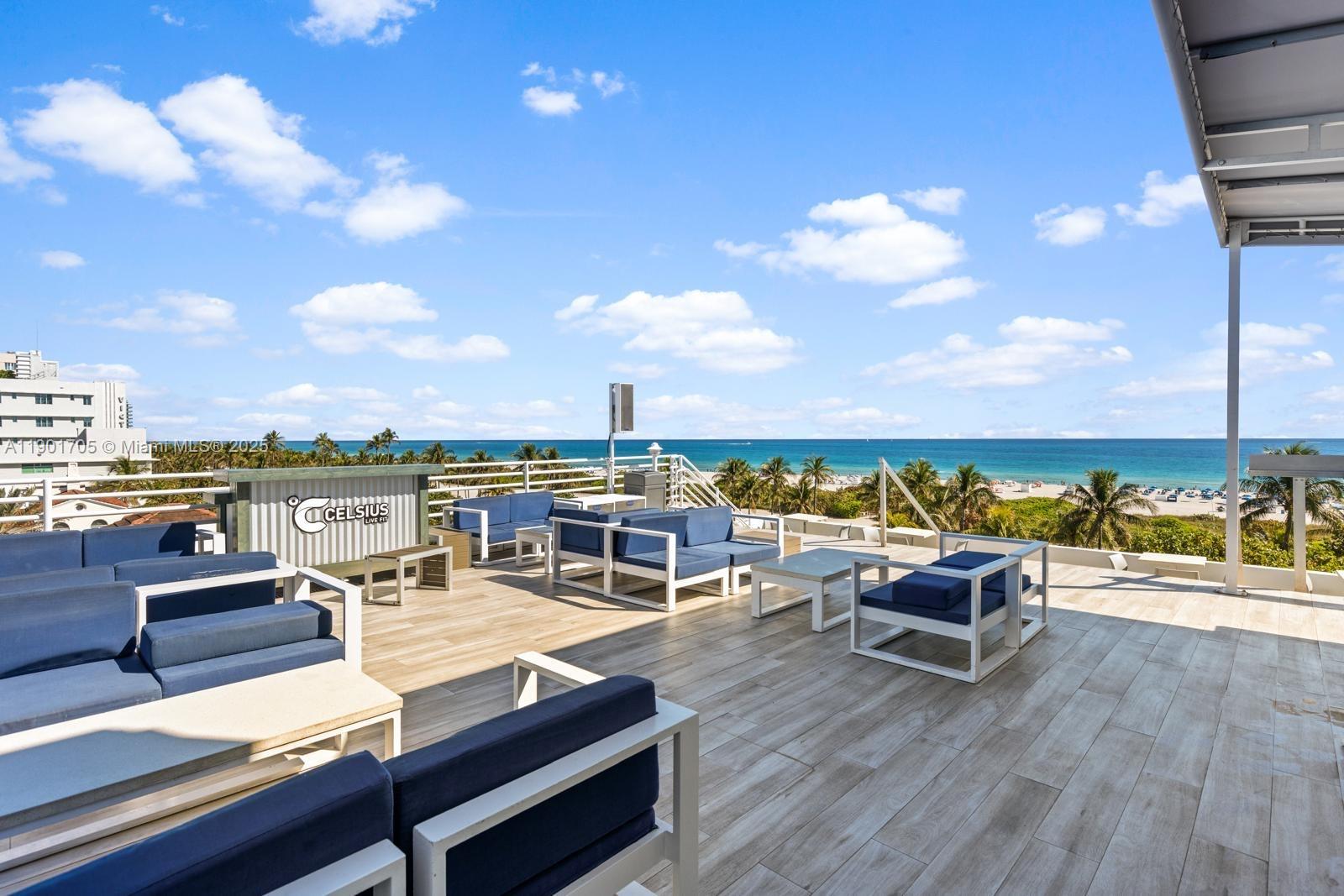 An outdoor rooftop terrace features blue cushioned seating, white frames, and a view of the ocean — 1024 Ocean Dr # A301, Miami Beach FL 33139, MIAMI BEACH, FL