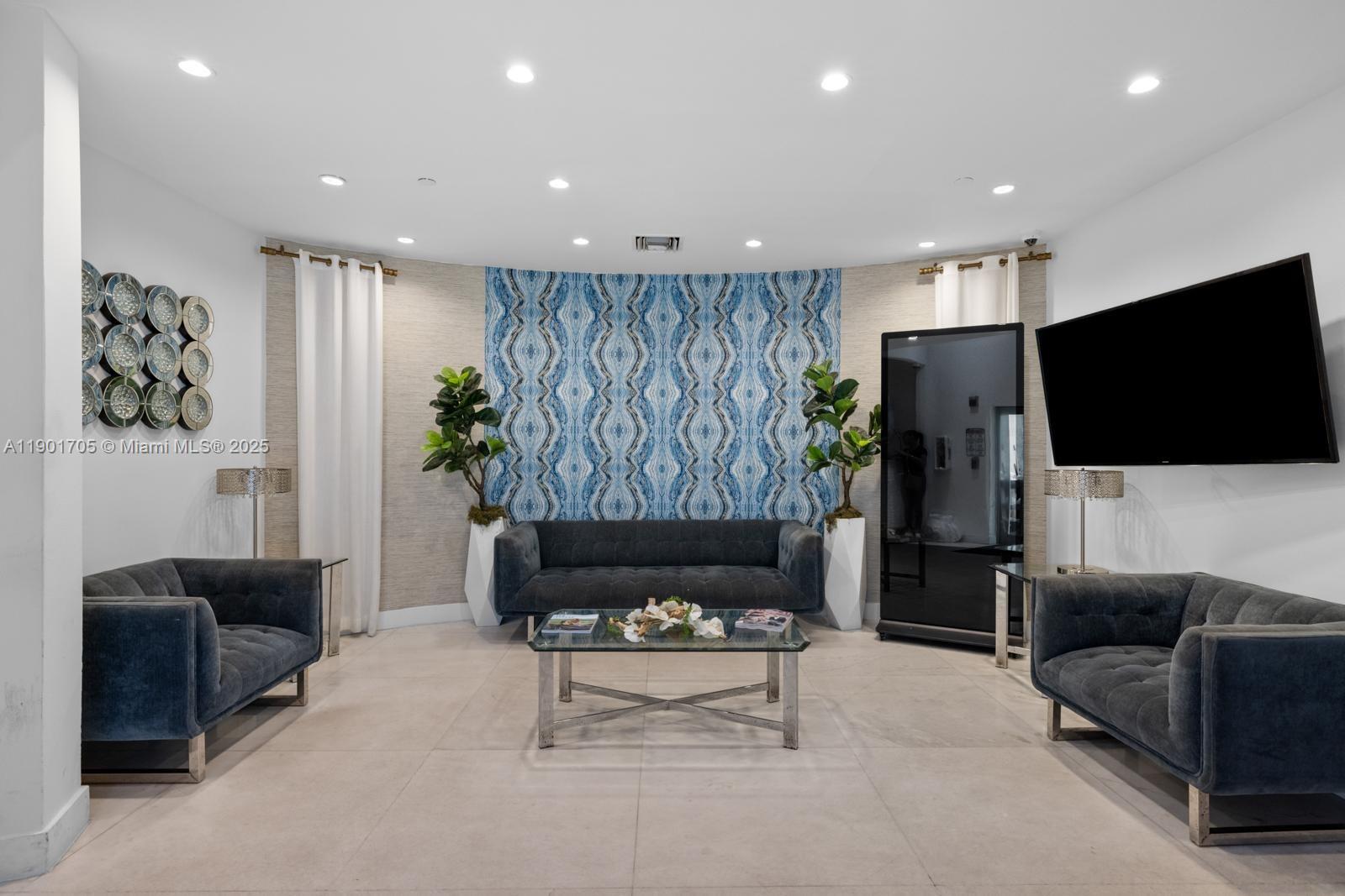 A waiting room features three dark gray tufted sofas, a glass coffee table, and wallpaper — 1024 Ocean Dr # A301, Miami Beach FL 33139, MIAMI BEACH, FL