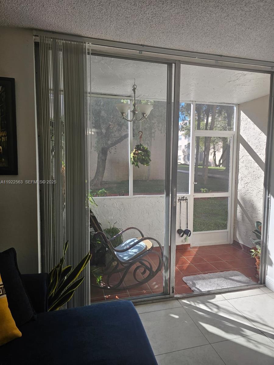 A living room looks through a sliding glass door onto a screened-in patio — 8411 NW 8th St # 111, Miami FL 33126, MIAMI, FL