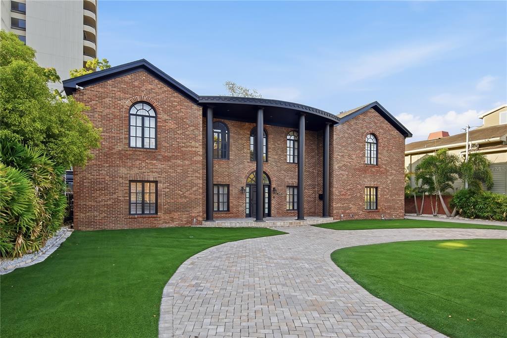 A two-story brick house with a curved porch, black columns, and a paved driveway — 2418 W PALM DRIVE, TAMPA, FL