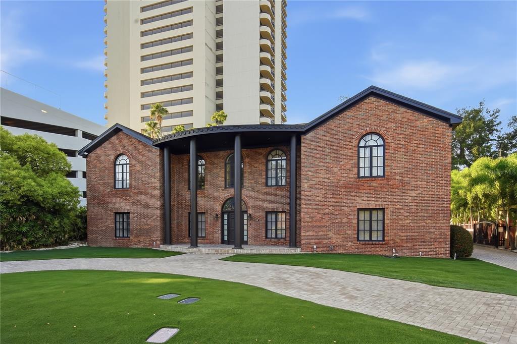 A two-story brick house with a covered front porch and arched windows sits on a lawn — 2418 W PALM DRIVE, TAMPA, FL