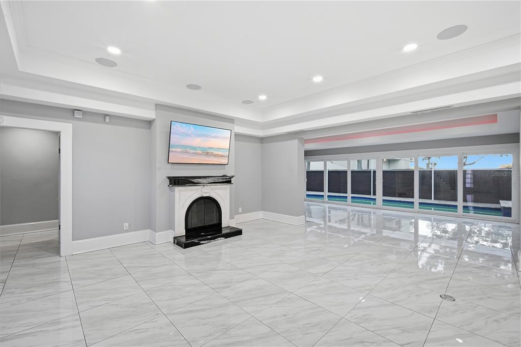 A spacious living room features white marble tile floors, a fireplace, and large sliding glass doors — 2418 W PALM DRIVE, TAMPA, FL