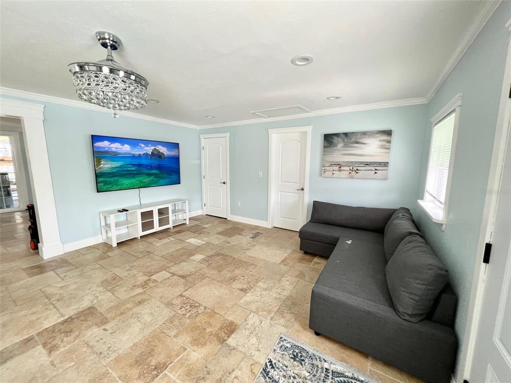A living room features light blue walls, tile flooring, a grey sectional sofa, and a television — 2963 BAHIA VISTA STREET, SARASOTA, FL
