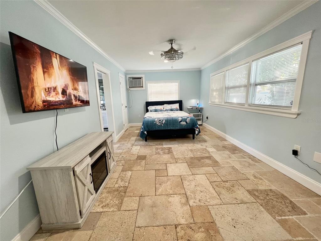 A bedroom features light blue walls, a tile floor, a bed, and a wall-mounted television — 2963 BAHIA VISTA STREET, SARASOTA, FL