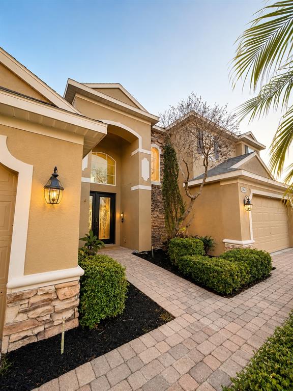 A tan stucco house with a stone facade, arched entryway, and a paved walkway — 1546 STARGAZER TERRACE, SANFORD, FL