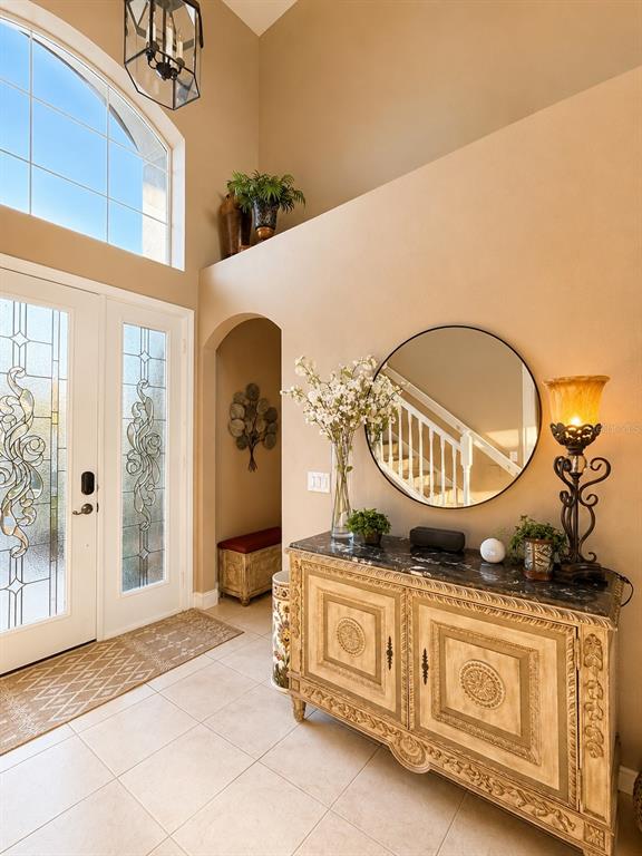 An entryway features a high ceiling, a decorative console table, a round mirror, and tile flooring — 1546 STARGAZER TERRACE, SANFORD, FL