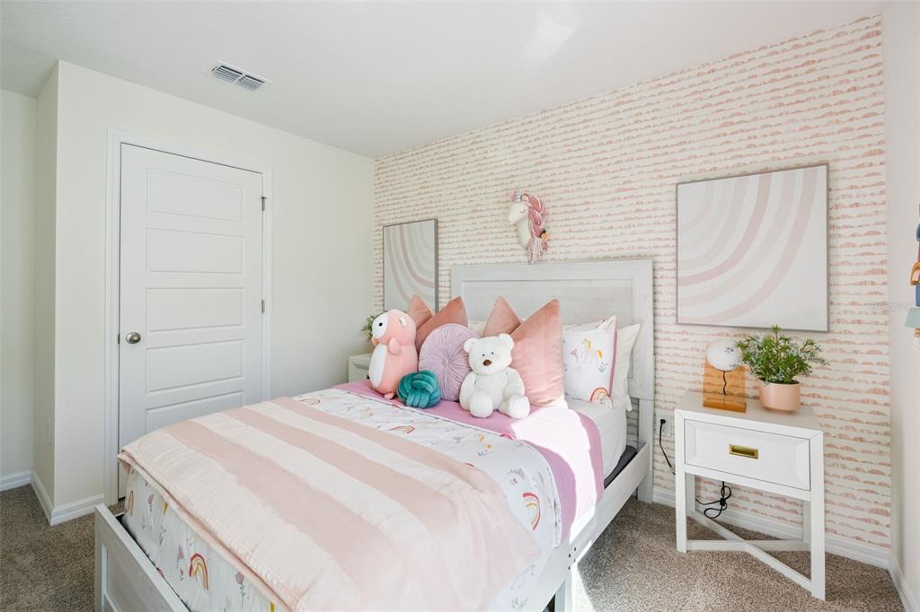 A bedroom features a bed with pink pillows, a unicorn wall mount, and patterned wallpaper — 1727 GRANDIOSE DRIVE, HAINES CITY, FL
