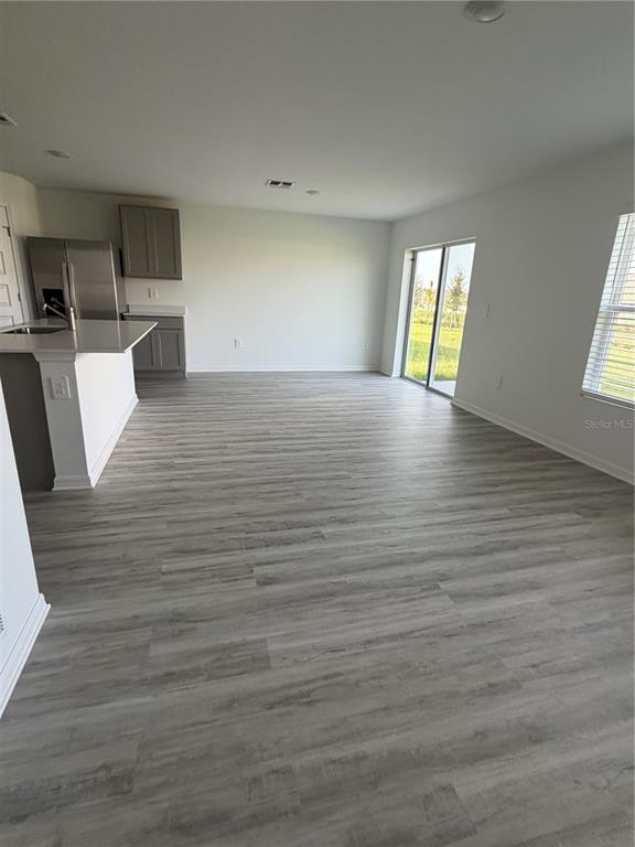An open-concept kitchen and living area features gray wood-look flooring and a sliding glass door — 1727 GRANDIOSE DRIVE, HAINES CITY, FL