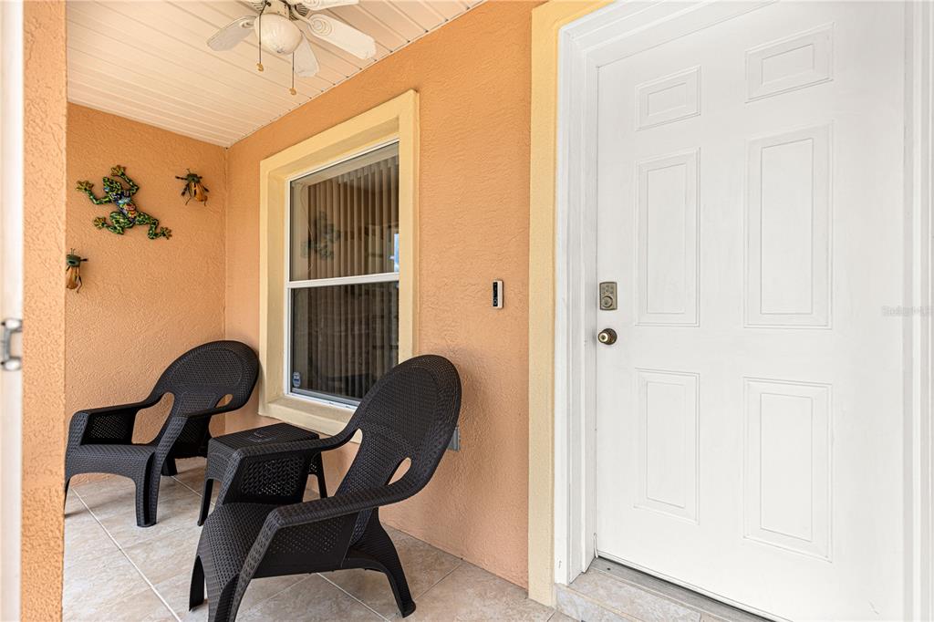 A covered porch features two black chairs, a small table, and a white front door — 4 CEDAR TRACE PASS, OCALA, FL