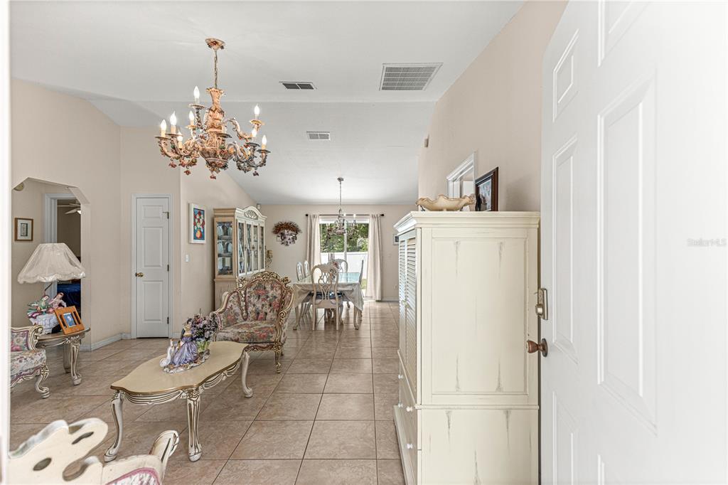 A living and dining area features tile floors, a crystal chandelier, and traditional furniture — 4 CEDAR TRACE PASS, OCALA, FL