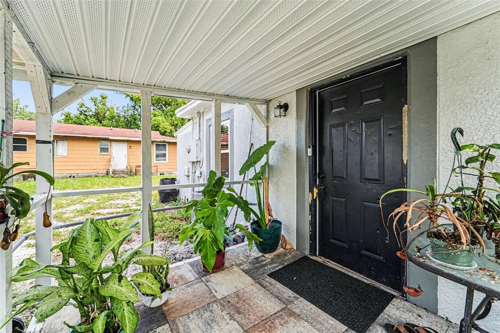 A covered porch with a black door, tiled floor, and several potted plants — 1024 GRANT AVENUE, MOUNT DORA, FL