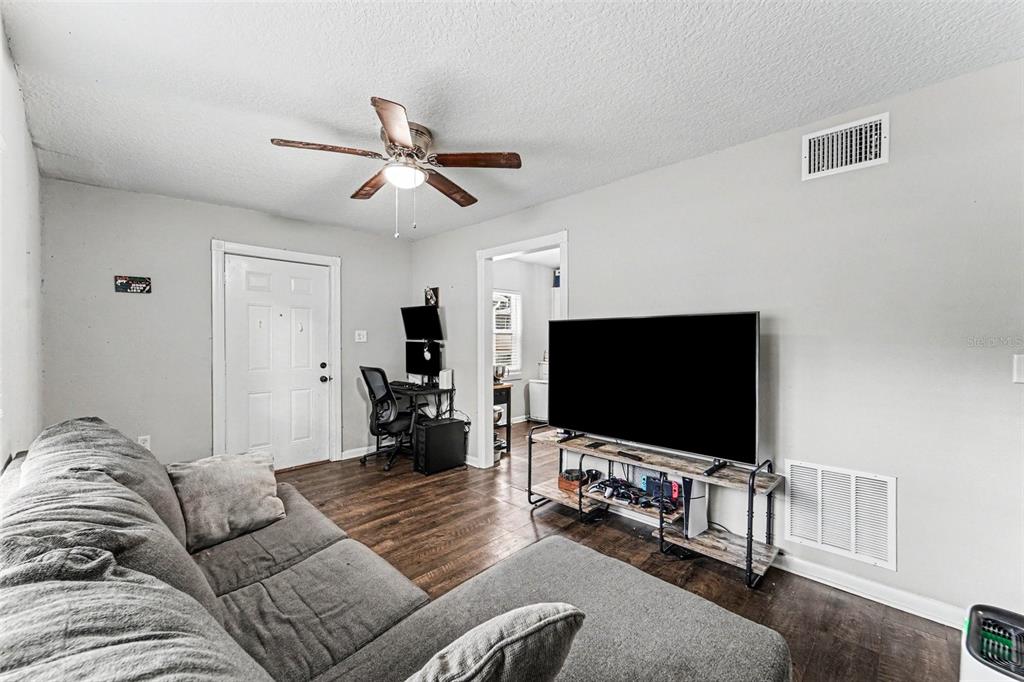 A living room features a gray sectional sofa, a television on a stand, and a desk — 1024 GRANT AVENUE, MOUNT DORA, FL