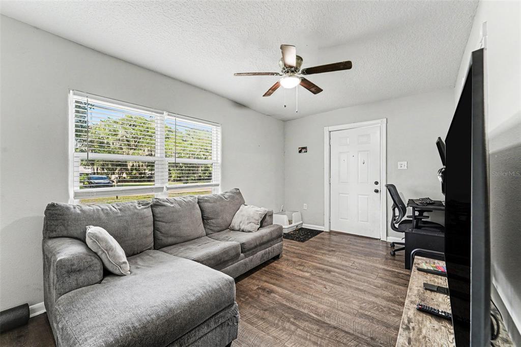 A living room features a grey sectional sofa, wood-look flooring, and a ceiling fan — 1024 GRANT AVENUE, MOUNT DORA, FL