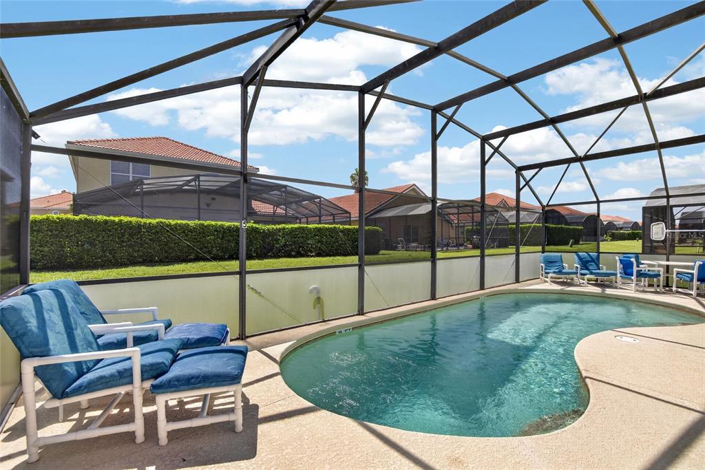 A swimming pool enclosed by a screened lanai with patio furniture on a concrete deck — 110 SARAGOSSA AVENUE, DAVENPORT, FL