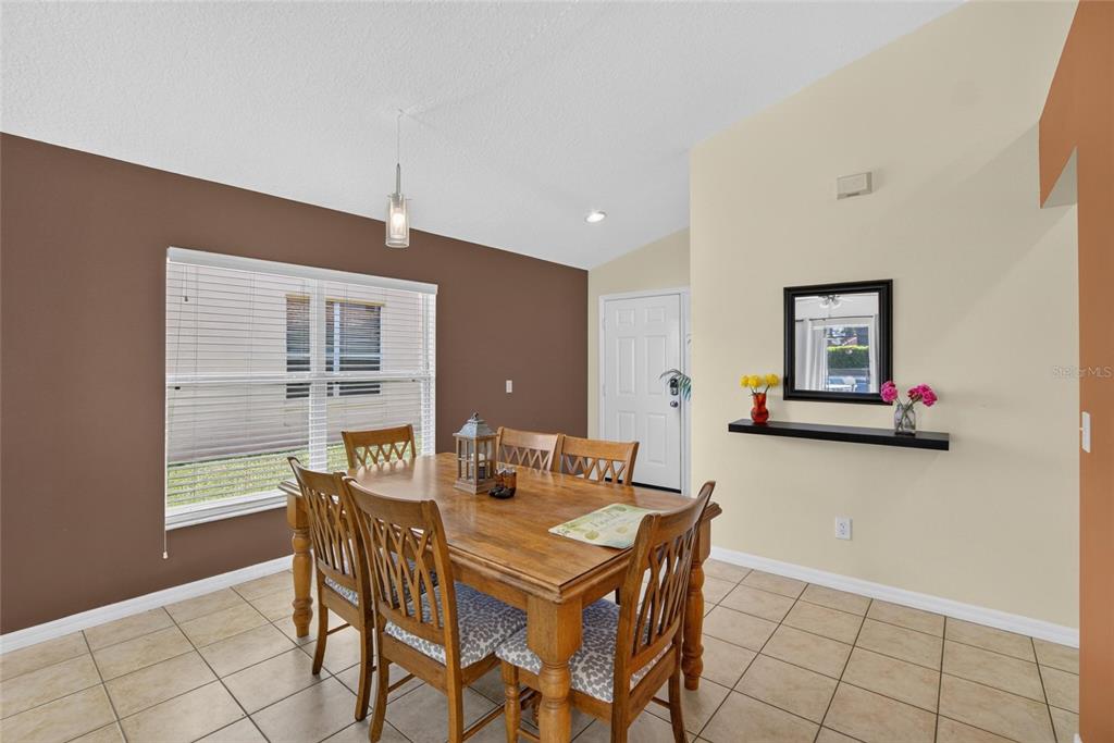 A dining room features a wooden table with chairs, tile flooring, and a wall mirror — 110 SARAGOSSA AVENUE, DAVENPORT, FL