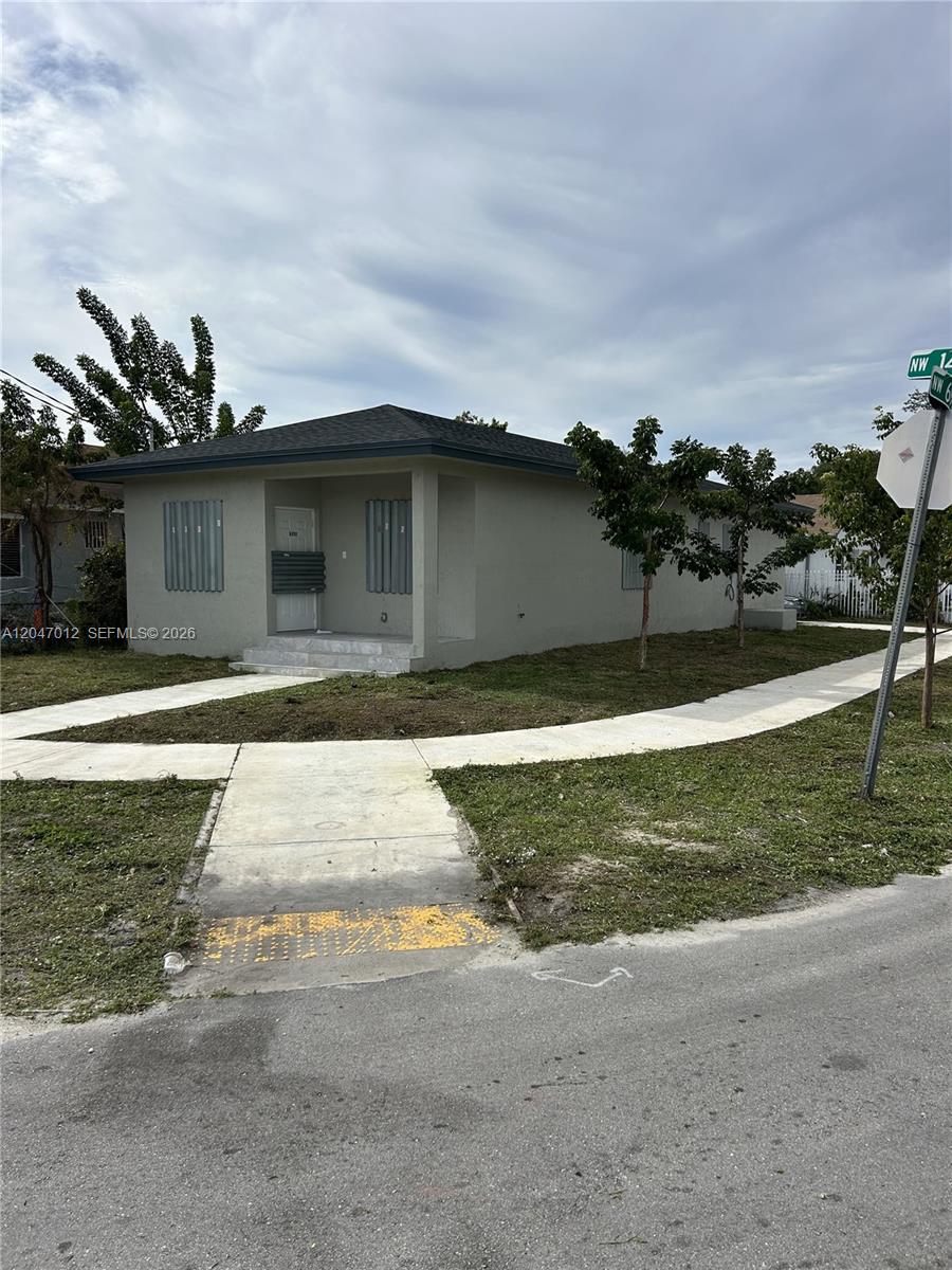 A single-story house with a gray exterior and window shutters sits on a corner lot — MIAMI, FL