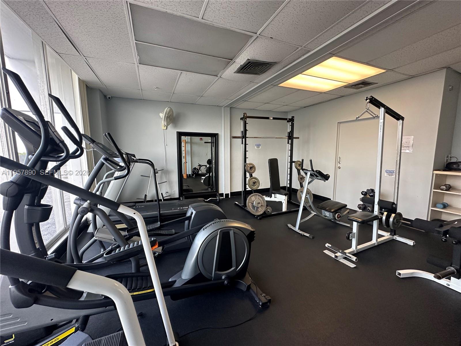 A gym room features various exercise machines, weight equipment, and a mirror on a black floor — 1720 Harrison St # 7A, Hollywood FL 33020, HOLLYWOOD, FL