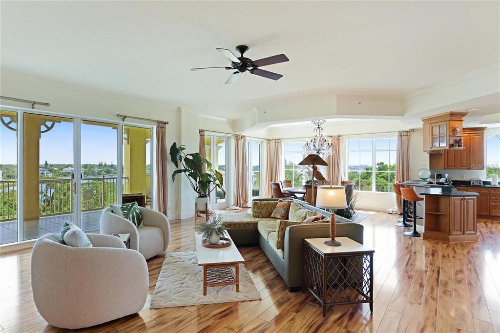 A bright open-concept living room features hardwood floors, a sectional sofa, and floor-to-ceiling windows — 1308 OLD STICKNEY POINT ROAD UNIT WP3, SARASOTA, FL