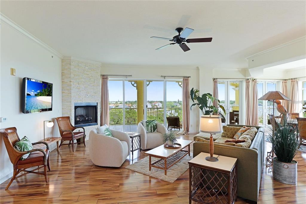 A living room features hardwood floors, a stone fireplace, and sliding doors to a balcony — 1308 OLD STICKNEY POINT ROAD UNIT WP3, SARASOTA, FL