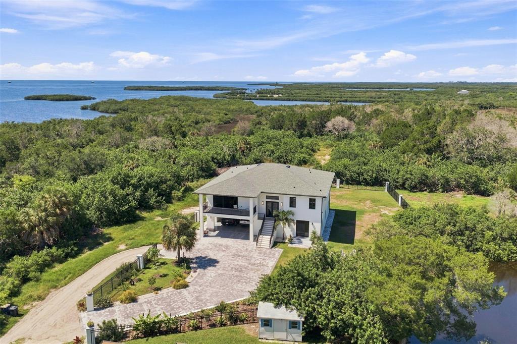 An aerial view shows a two-story house with a paved driveway surrounded by dense vegetation — 5035 BAY BOULEVARD, PORT RICHEY, FL
