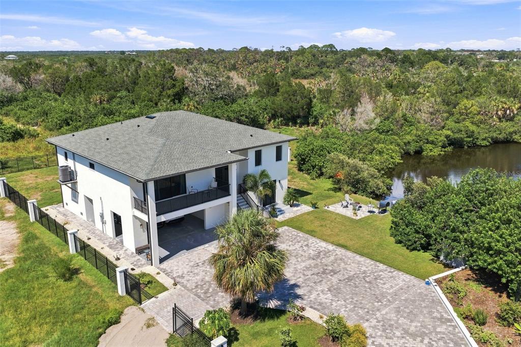 An aerial view of a two-story white house with a paved driveway and a backyard pond — 5035 BAY BOULEVARD, PORT RICHEY, FL