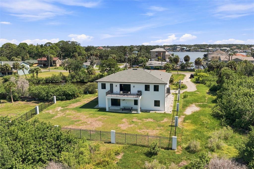 An aerial view shows a two-story white house with a balcony and fenced yard — 5035 BAY BOULEVARD, PORT RICHEY, FL