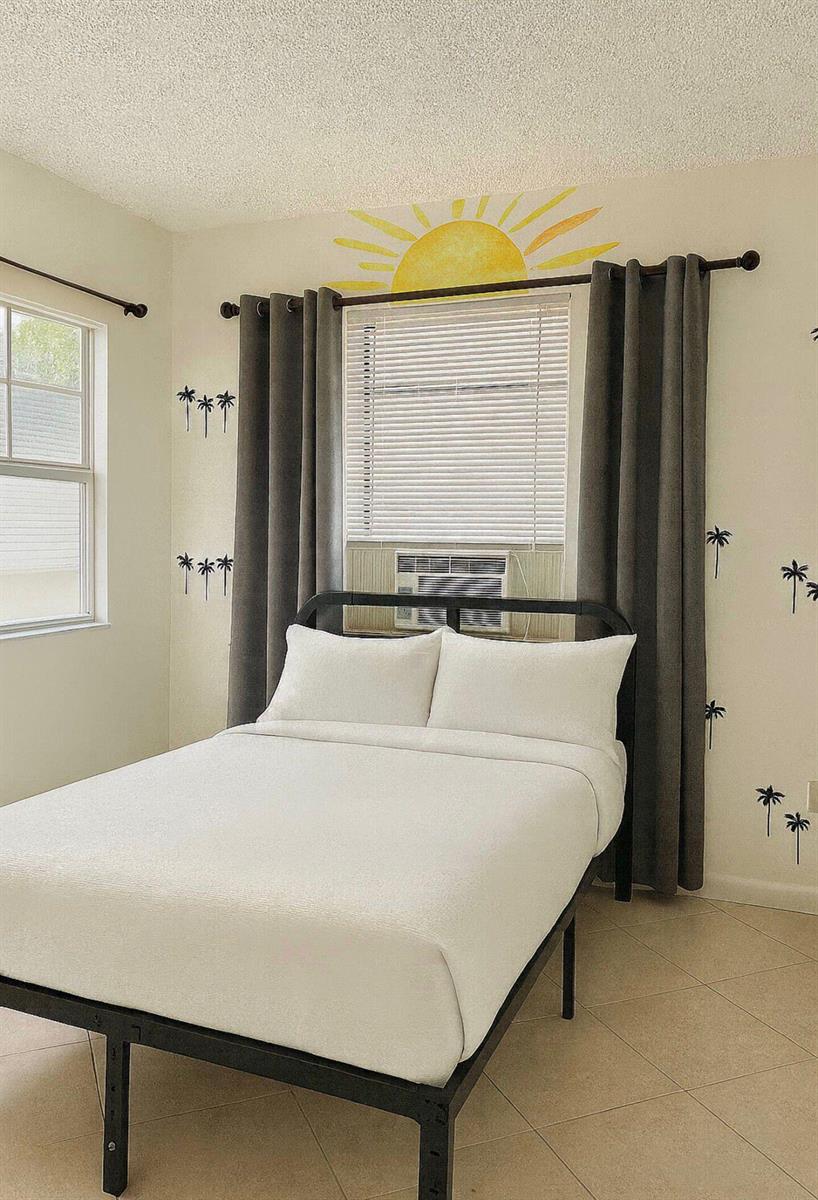 A bedroom features a bed against a window with a sun mural and palm tree decals — 272 NE 44th Street, Deerfield Beach FL 33064, DEERFIELD BEACH, FL