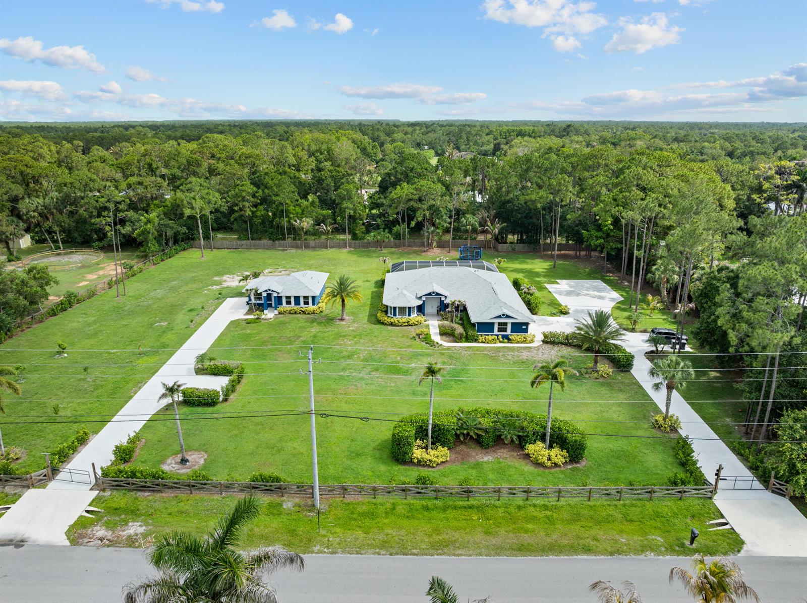 An aerial view shows two blue houses on a large, grassy lot with palm trees — 11354 Sandy Run, FL 33478, FL