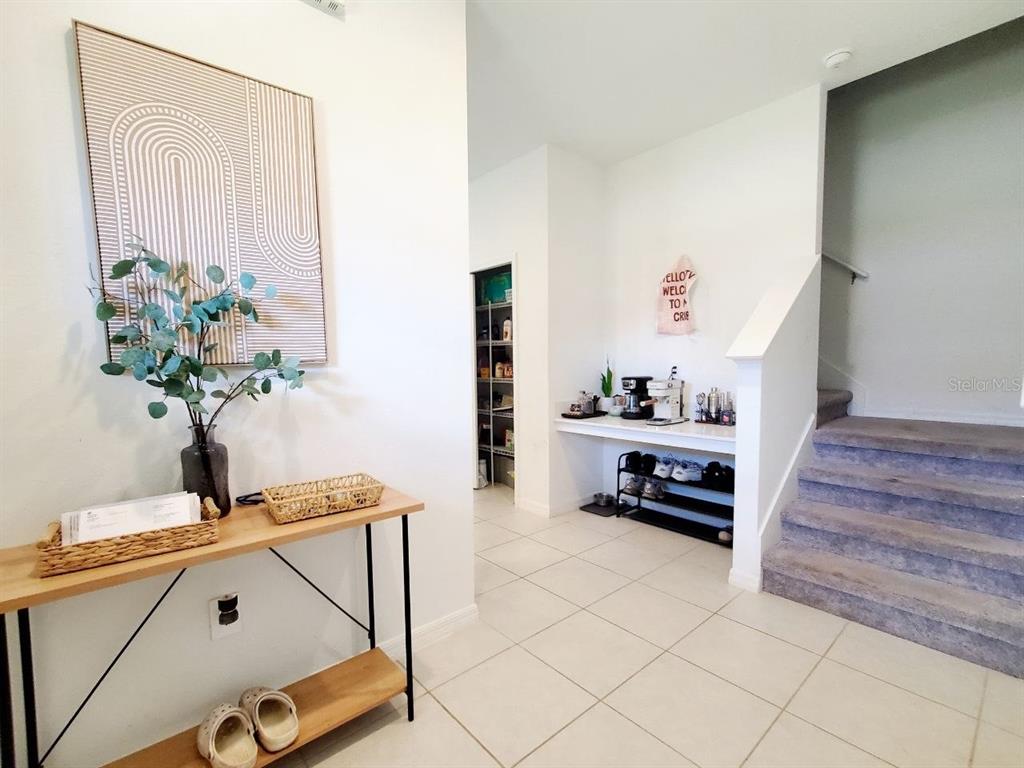 An entryway features a console table, a coffee station, a pantry, and a carpeted staircase — 10268 TRUMPET HONEYSUCKLE WAY, SAN ANTONIO, FL