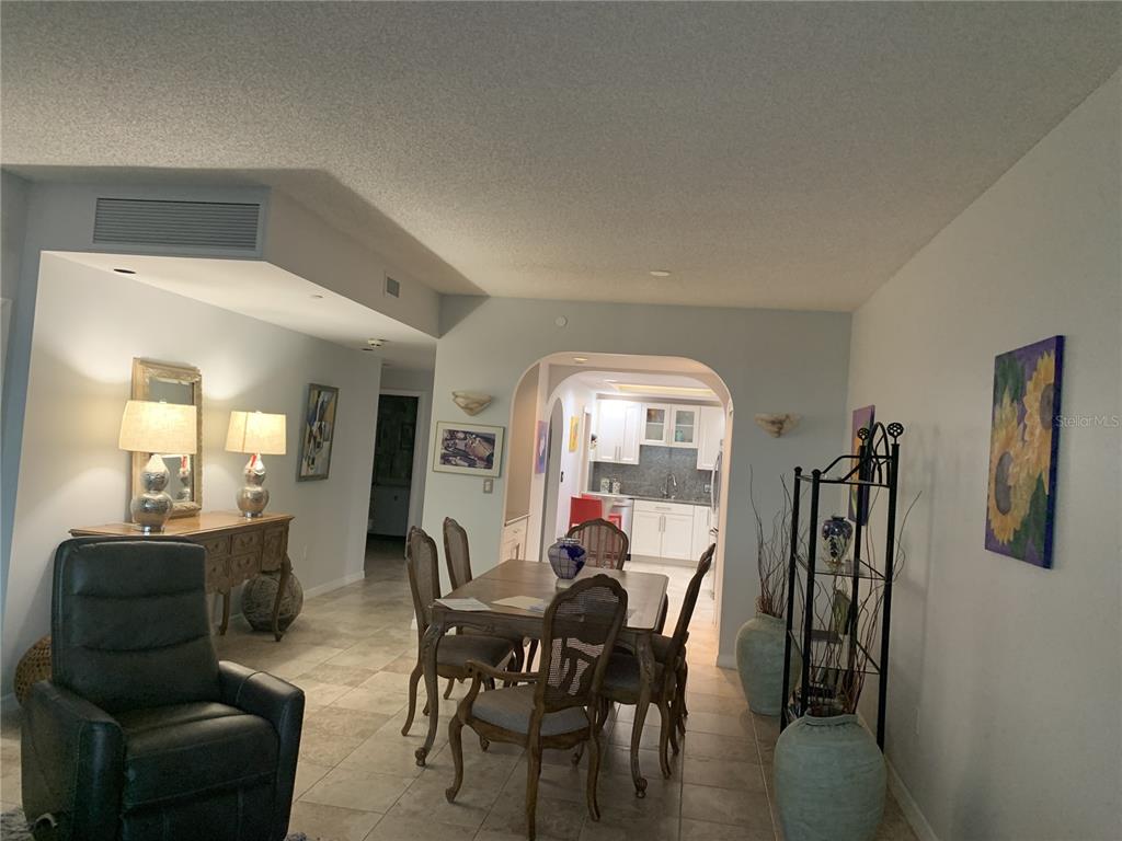 A dining area with a wooden table and chairs sits between a living space and kitchen — 1 BEACH DRIVE SE UNIT 1907, ST PETERSBURG, FL