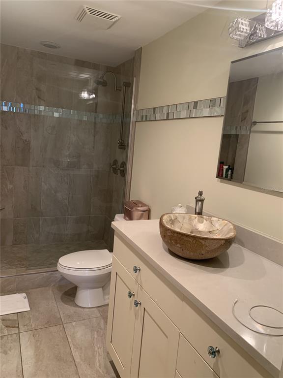 A bathroom features a glass-enclosed shower, a vessel sink on a vanity, and tile flooring — 1 BEACH DRIVE SE UNIT 1907, ST PETERSBURG, FL