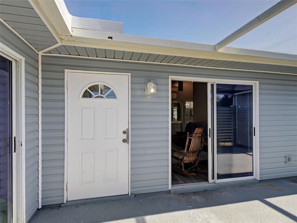 A white door and a sliding glass door are set into light blue vinyl siding — 3300 LOVELAND BOULEVARD UNIT 3004, PORT CHARLOTTE, FL