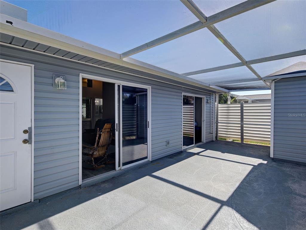 A covered patio features gray siding, sliding glass doors, and a concrete floor — 3300 LOVELAND BOULEVARD UNIT 3004, PORT CHARLOTTE, FL